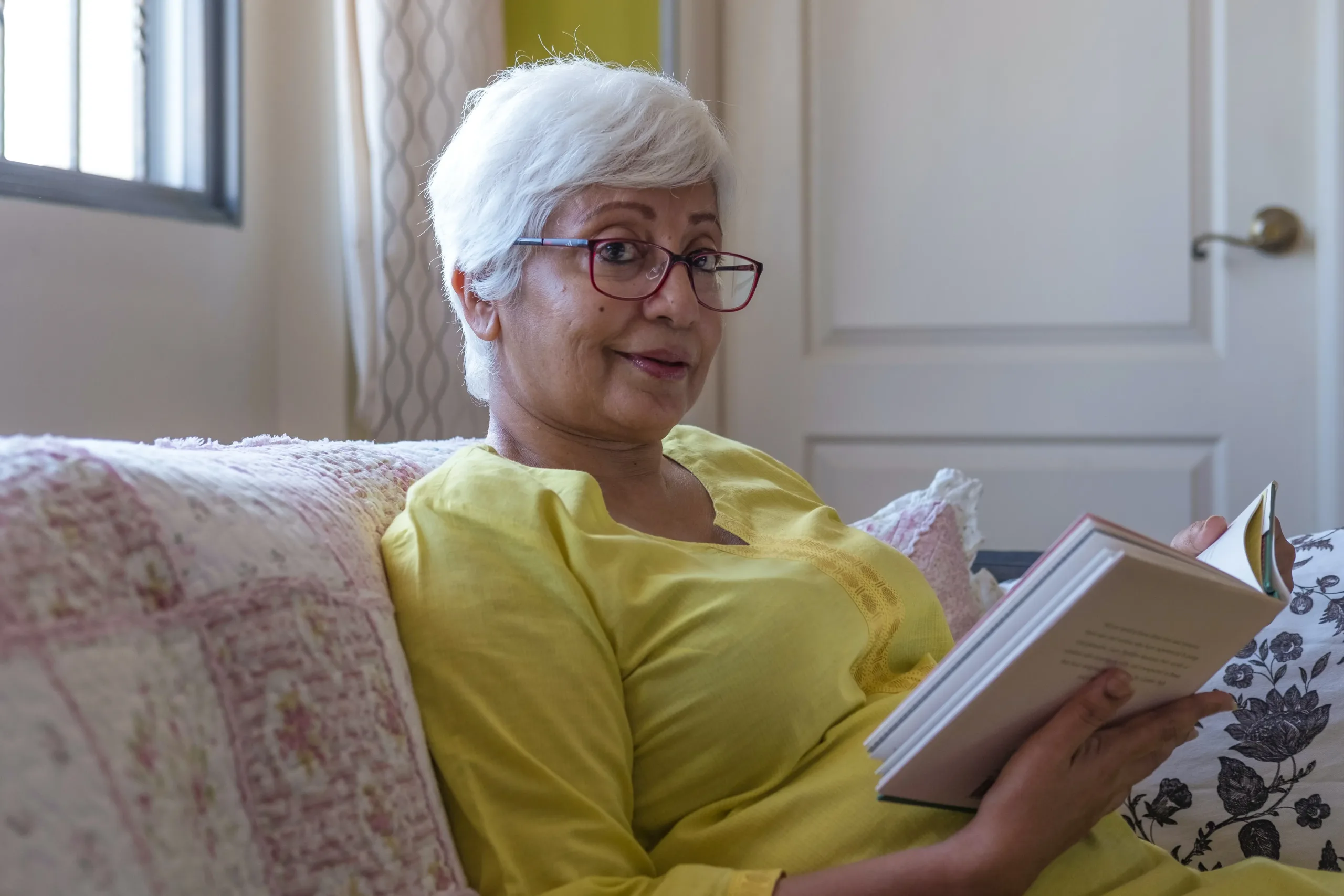 Older woman reading a book on the couch